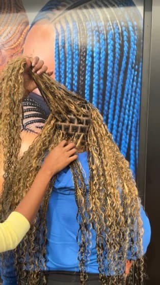 Close-up back view of long blonde curly braids