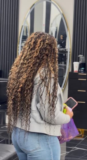 Long highlighted curly braids photographed from the side inside the salon